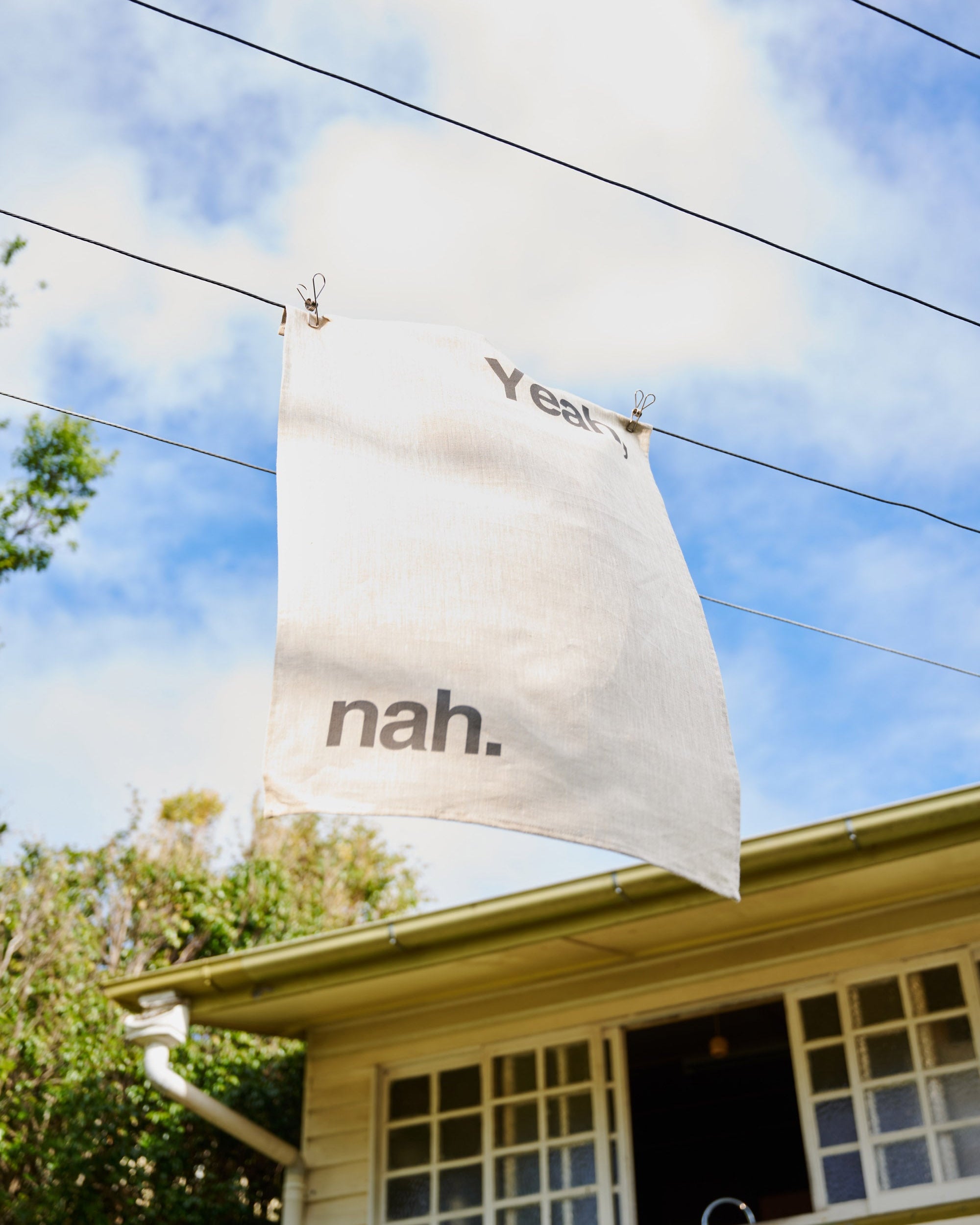 White banner with text 'nah.' hanging from a house against a blue sky.